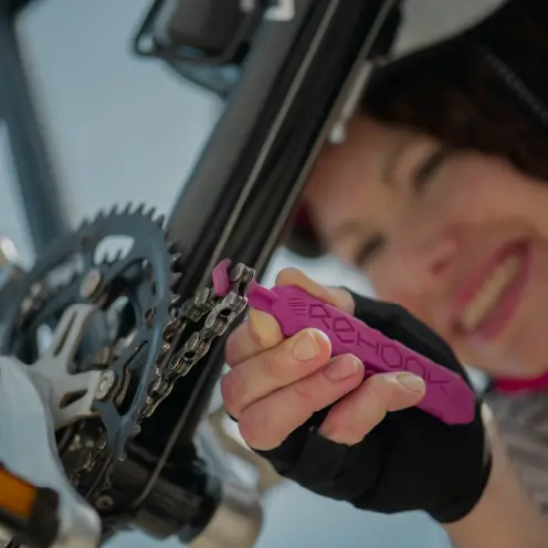 Femme souriante réparant la chaîne d’un vélo cargo électrique Yükargo