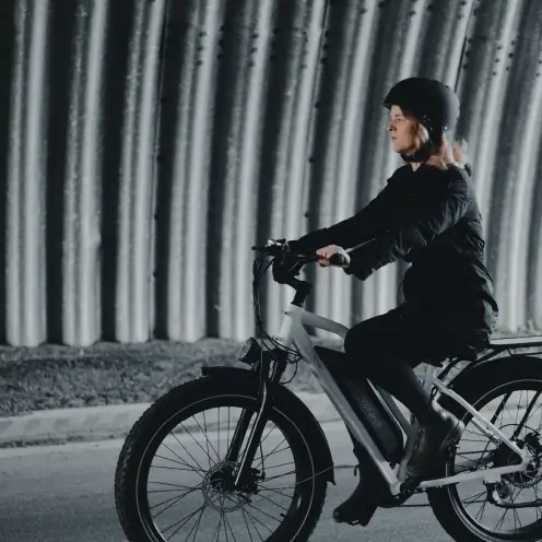 Femme roulant en vélo cargo blanc Yükargo sous un pont couvert, illustrant l’expérience Yükargo