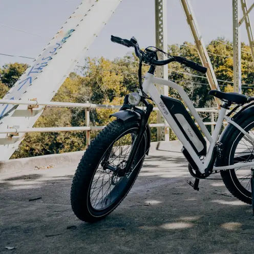 Vélo cargo électrique blanc Yükargo garé sous un pont avec des arbres en arrière-plan