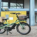 Vélo cargo électrique Yükargo transportant un carton devant une borne pickup, pratique avec la LOA vélo cargo